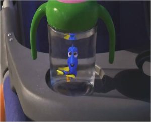 An animated scene from the Pixar film "Finding Dory." A cupholder of a baby stroller with a sippy cup that has a blue tang inside.
