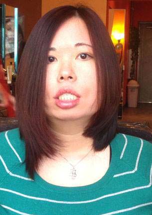 Middle-aged Chinese American woman with long hair. She is wearing a green sweater and white-stripes. A living room background is behind her.