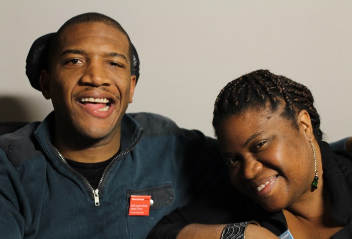 Image Description: A photo featuring Lateef McLeod and Aqueila Lewis, taken on March 5th, 2015. Lateef McLeod is on the left, wearing a zip-up blue fleece, a black tee-shirt, and a red StoryCorps pin. Lateef appears to be African American, and he is smiling. Aqueila Lewis is on the right, wearing a black sweater, a long earring, and her hair is braided and pulled back. She appears to be African American, her face is tilted to the left, and she is smiling.