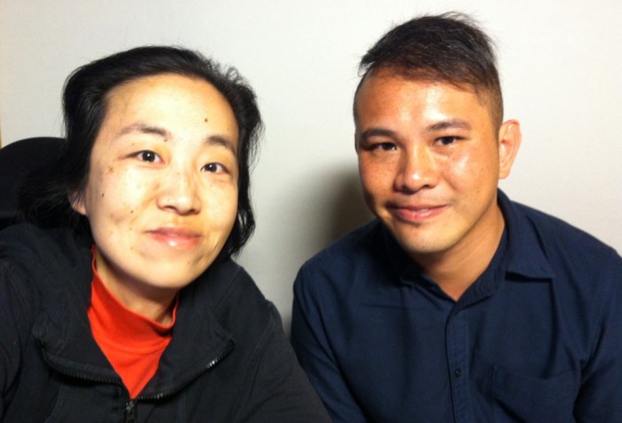 Photo of two Asian Americans. On the left is a middle-aged Asian American woman wearing a black hoodie and red turtleneck. On her right is a younger Asian American man with short hair and wearing a navy shirt.