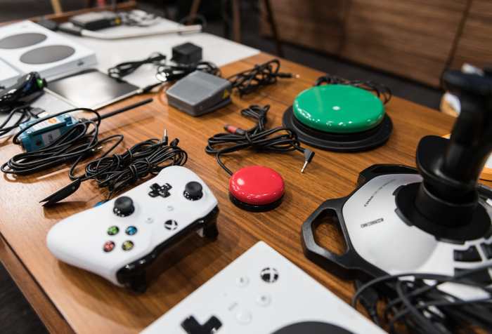 Photo courtesy of Microsoft. A table with the Xbox Adaptive Controller and an array of accessories such as a joystick, microswitch, foot pedal and other items.