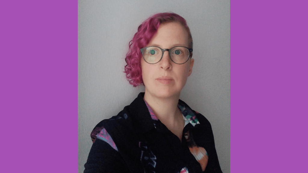 Graphic with a purple background. In the center is a photo of a white woman against a grey wall, her head is tilted slightly to the right, looking away from the camera. She has curly hair, dyed magenta, uses greenish glasses and is wearing a black shirt.