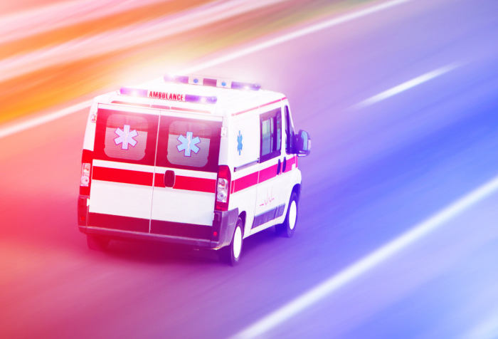 Photo of an ambulance on a highway with hues of red and blue light