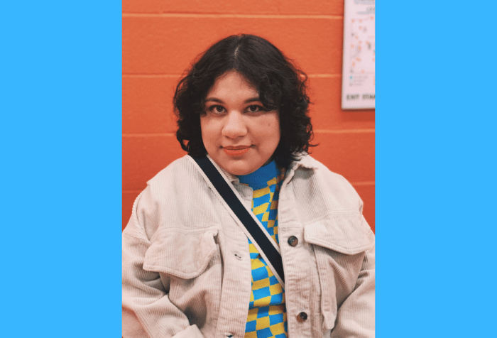 Graphic with a sky blue background featuring a photo in the center of Jocelyn Mondragon. A Mexican woman with curly short black hair, smiling straight at the camera. In front of an orange painted brick wall, Jocelyn is wearing a beige corduroy jacket with a blue and yellow checkered sweater underneath. A black and white striped strap is across her shoulder.