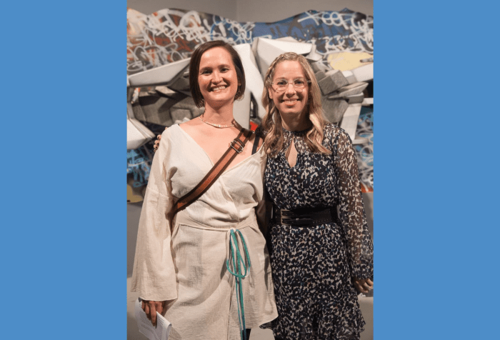 Graphic with a blue-gray background featuring a photo of curators Vanessa Chang and Lindsey D. Felt standing shoulder to shoulder in front of a graffiti installation, beaming at the camera. Lindsey has wavy blonde hair and wears translucent glasses and a gauzy black and white dress with a black double buckle belt. Vanessa has a short dark brown bob and wears a gold choker necklace and a long sleeved white kimono top. A brown bag strap crosses her chest.